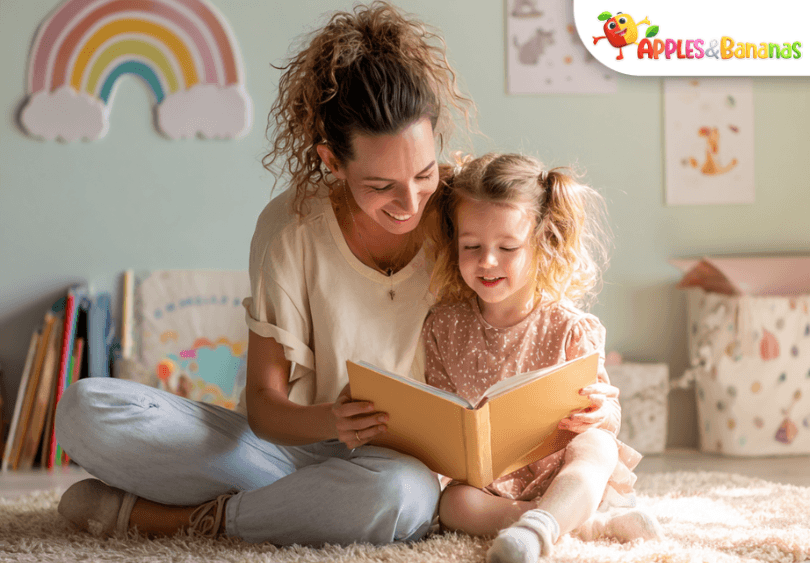 A young child reading storybooks on a cozy rug in a sunlit room, surrounded by colorful books and a smiling adult nearby, symbolizing a love for reading and learning.
